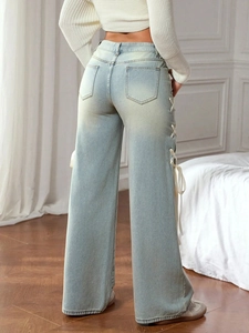 Detail of white ribbon lace-up design on the side of light blue wide-leg jeans