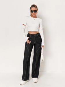 Detail of high-waist wide-leg jeans with contrast stitching and white cutout top