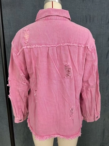 Detailed back view of pink distressed denim jacket with frayed holes and raw hem details