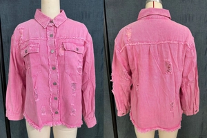 Close-up of distressed hot pink denim shirt with ripped details and raw hem