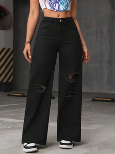 Detail of high-waisted black wide-leg jeans with distressed knee rips and frayed edges