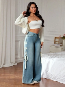 Detail of light blue wide-leg jeans with cream ribbon bow tie-up side cut-outs
