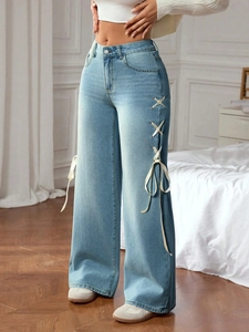 Detail of light blue wide-leg jeans featuring side white ribbon lace-up and bow design