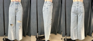Detail of ripped knees and distressed wash on light blue high waist wide leg jeans