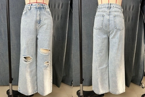 Detail showing distressed ripped design on high waist light blue wide leg jeans