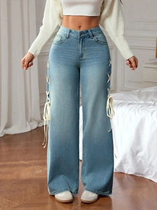 Detail view of light blue wide-leg jeans with side ribbon lacing and high-waist cut
