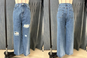 Detail of high-waisted distressed wide-leg jeans with vintage wash and ripped knees