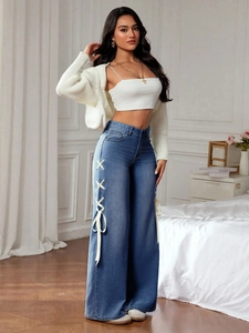 Detail of high-waisted blue jeans with white ribbon lace-up design on the side of the legs