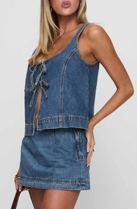 Détail du crop top licou en jean bleu avec laçage frontal et coutures blanches