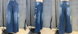 Detail of blue wide-leg jeans featuring stylish white ribbon lace-up sides and high waist
