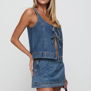 Détail d'un ensemble top dos nu et jupe en denim bleu avec texture délavée et zip latéral