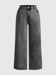 Close-up of red cherry embroidery on high-waist washed dark grey wide-leg denim jeans
