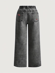 Close-up of cherry embroidery on the back pocket of wide-leg acid wash jeans