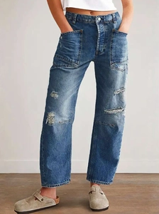Detail view of baggy distressed jeans with large front pockets and ripped knee design