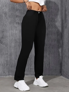 Détail du jean noir à taille haute avec fermeture boutonnée et texture brodée