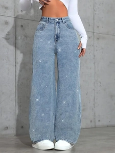 Detailed view of shimmering rhinestone embellishments on light blue wide leg denim jeans