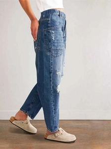 Detail shot of mid-blue ripped jeans with elastic waistband and large side patch pockets