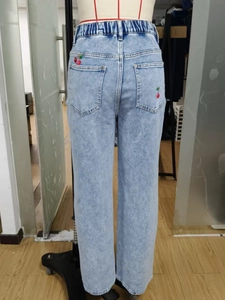 Detail of red cherry embroidery on back pockets of light blue high waist jeans