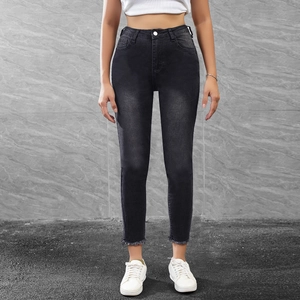 Close-up of women's black skinny jeans featuring raw hem ankle and high waist design