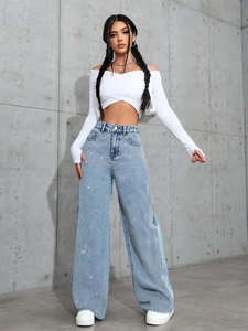 Detail of high waist wide leg blue jeans with sparkling rhinestones and white crop top