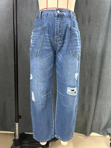 Close-up of distressed denim jeans featuring ripped details and symmetrical patch pockets