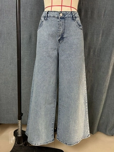 Detail of light blue wide-leg jeans featuring dense silver rhinestone embellishments