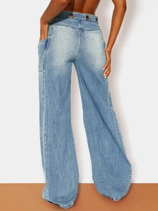 Detail view of high-waist light blue wide-leg jeans with unique triple metal eyelets on waist