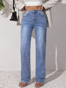 Detail of light blue high-waisted jeans with stylish curved seam stitching on legs