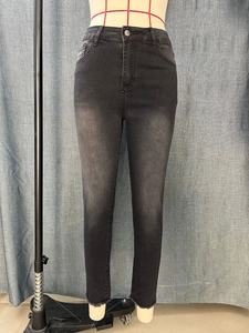 Detail of slim fit black denim jeans for women featuring raw hem edges and high waist design