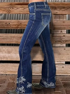 Detail of white horse embroidery on dark blue flared jeans with vintage wash effect