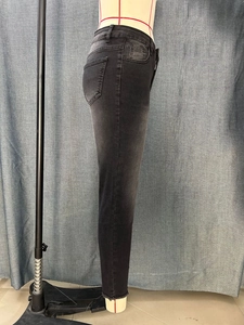 Detail shot of black skinny jeans featuring classic five-pocket design and raw hem edges