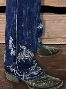Detailed white western embroidery featuring horses and cowboys on blue denim flare jeans