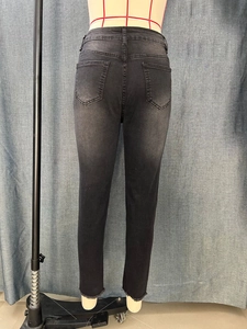 Detailed view of women's black cropped skinny jeans with frayed hems and washed finish