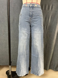 Detail of high waist light blue wide leg jeans with vertical washed pleated texture
