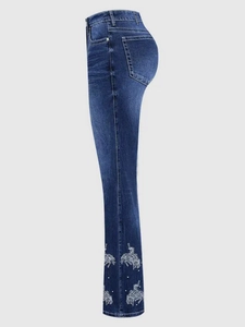 Detail of blue flare jeans featuring white horse embroidery and beaded embellishments