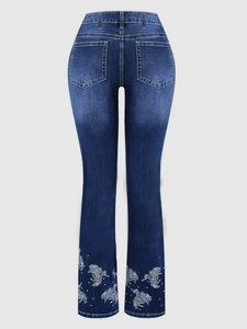Detailed embroidery of white horses and beads on the cuff of dark blue flare jeans
