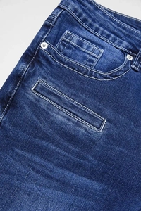 Macro view of front pocket detail on blue flare jeans with rivets and stitching
