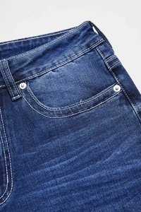 Detailed macro view of dark blue denim stitching with metal rivets and waist pocket