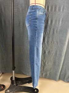 Détail de la couture latérale et du tissu denim délavé bleu sur un jean coupe droite