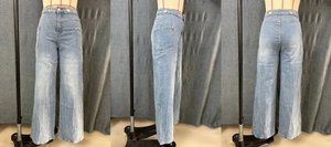 Detail view of high waist wide leg jeans with decorative metal ring on front waist