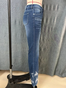 Detail of dark blue flared jeans featuring white horse embroidery and denim cat whiskers