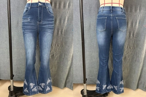 Detailed view of dark blue flare jeans featuring white horse embroidery and pearl accents
