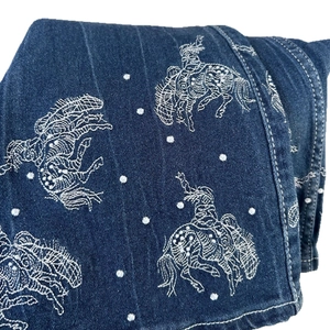 Women's flare jeans in dark blue denim featuring detailed western cowboy embroidery