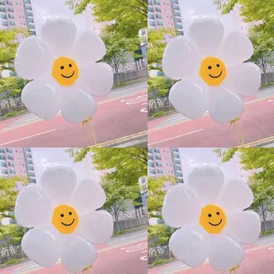 White daisy foil balloon with a yellow smiley face center in an outdoor street setting