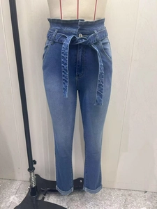 Detail of high waist light blue denim pants with a drawstring bow and rolled cuffs