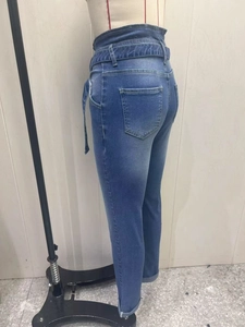 Detail of high waisted blue jeans featuring a triple-button waist and matching fabric belt