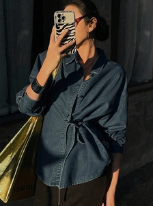 Détail d'une chemise en jean bleu foncé avec lien à la taille et boutons avant