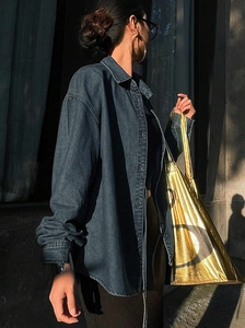Détail d'une chemise en jean gris avec un sac fourre-tout luxueux en métal doré brillant