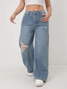 Detail of light blue high waist wide leg jeans with distressed ripped knees and vintage wash