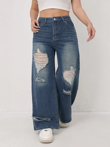 Detailopname van distressed denim en grote scheuren in de wijde jeans met hoge taille